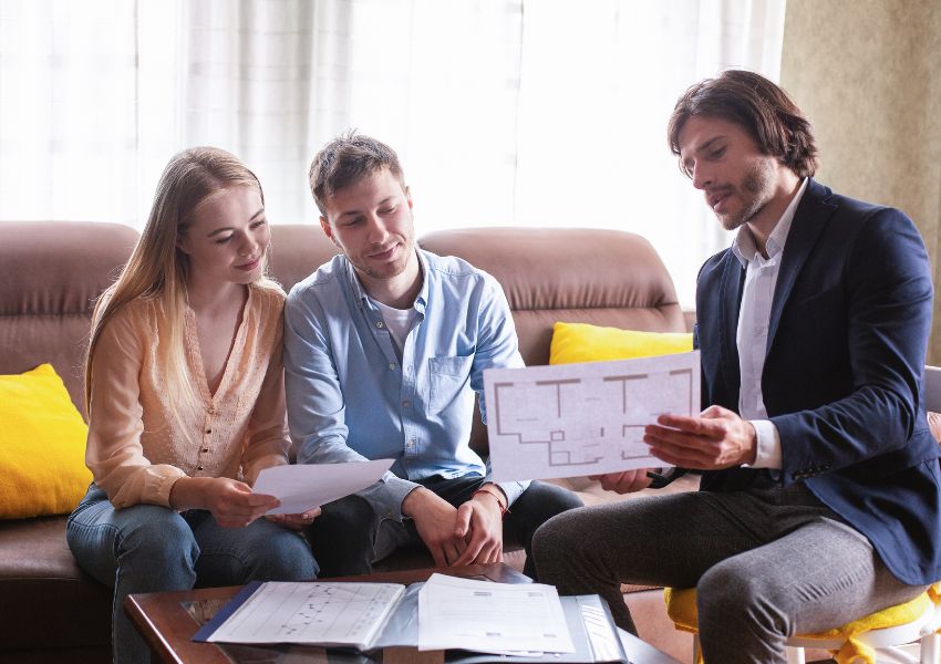 real estate specialist showing two buyers property blueprints